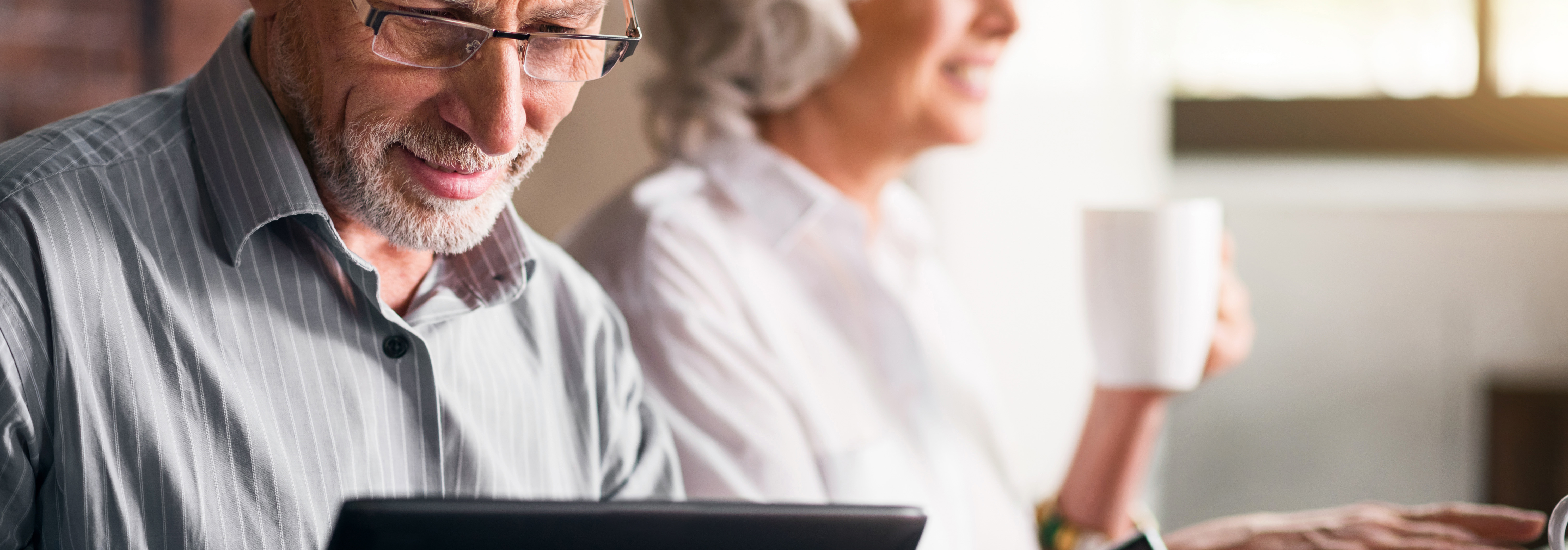 Older couple together while grey haired man uses laptop to search structured settlements for sale and what stuctured settlement qualify for cash lump sum.