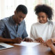 Happy young couple signing financial agreement with agent.