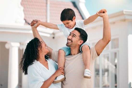 Happy family celebrating together outside their home, representing the financial security and opportunities achieved through selling annuity for cash lump sum.