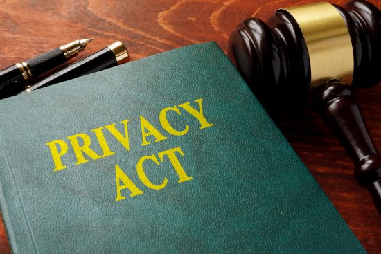 A book labeled 'Privacy Act' next to a gavel, symbolizing legal frameworks and court actions related to violations of privacy and lawsuits.