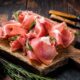 Prosciutto on a wooden board, highlighting the Eataly lawsuit where a patron was injured after slipping on a piece of the Italian delicacy.