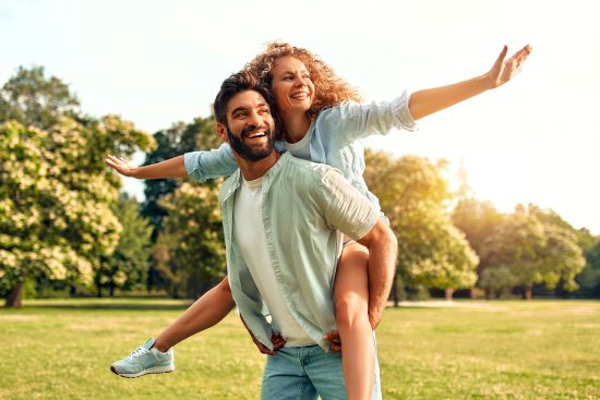 Happy couple enjoying a sunny day in the park, symbolizing improved financial freedom and stability achieved by selling an annuity.