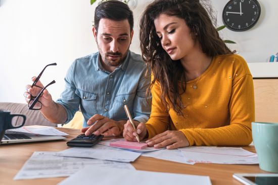 A couple reviewing financial documents and using a calculator, considering options for cashing out an annuity for a lump sum payment.