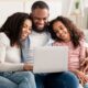 Smiling family using a laptop together at home, exploring financial solutions with DRB Capital for structured settlements and annuity payments.