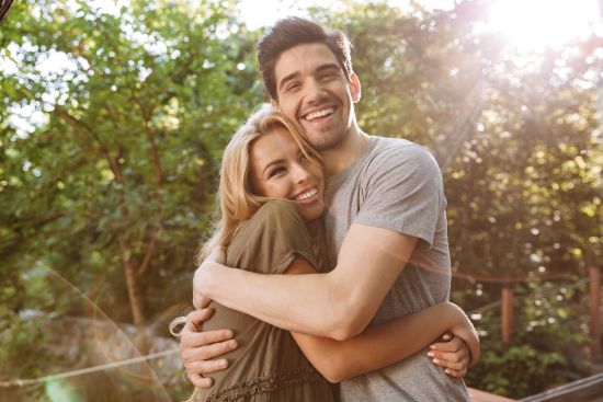 Young couple hugging outdoors, relieved and stress-free after selling their annuity to ease financial burdens.