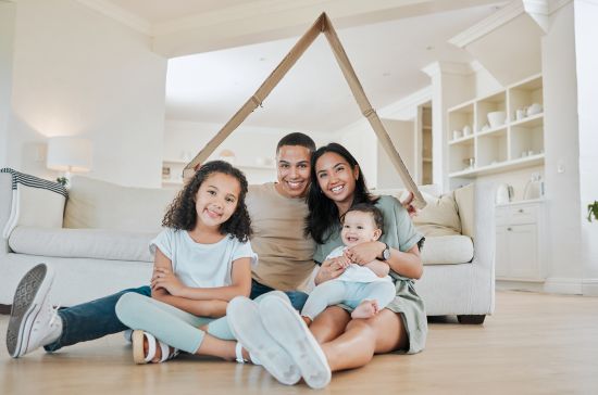Happy family sitting in their home, considering selling an annuity for a lump sum to pay off their mortgage
