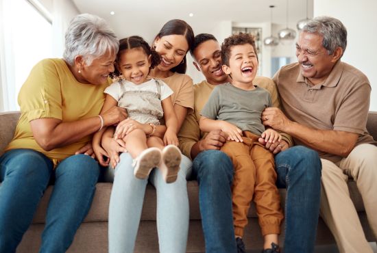 Happy multi-generational family sitting together on a couch, enjoying financial security after selling a structured settlement.