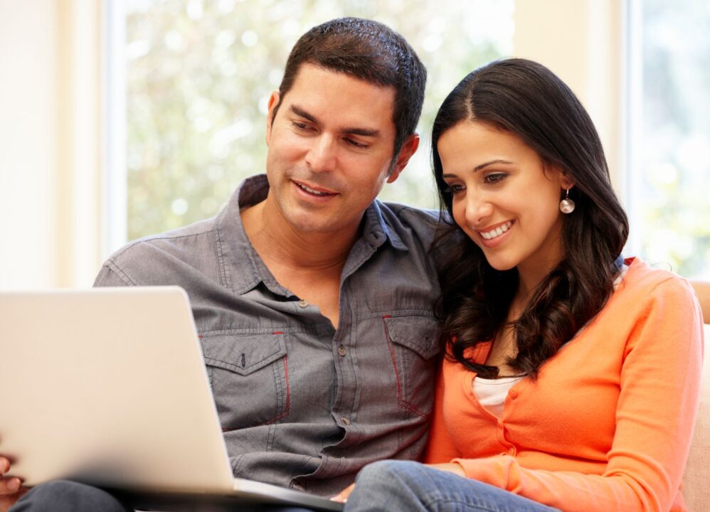 Smiling couple researching online about cashing out an annuity for a lump sum payment and financial options.