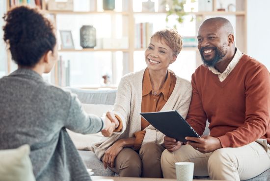 Smiling couple meeting with a financial advisor, discussing options for selling their annuity to achieve financial debt relief.
