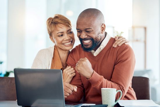Smiling couple considering whether to sell an annuity for a lump sum of cash to pay off their mortgage.