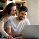 Young couple researching financial options on a laptop, considering annuity lump-sum payout with DRB Capital for their future needs.