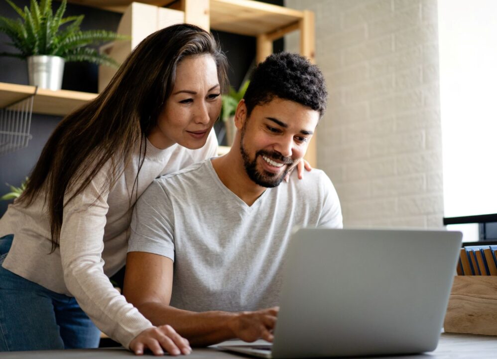 Young couple researching financial options on a laptop, considering annuity lump-sum payout with DRB Capital for their future needs.