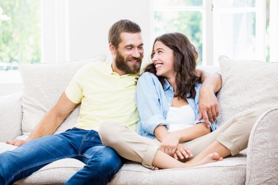 Happy couple relaxing on a couch, relieved after selling structured settlement payments to eliminate debt.