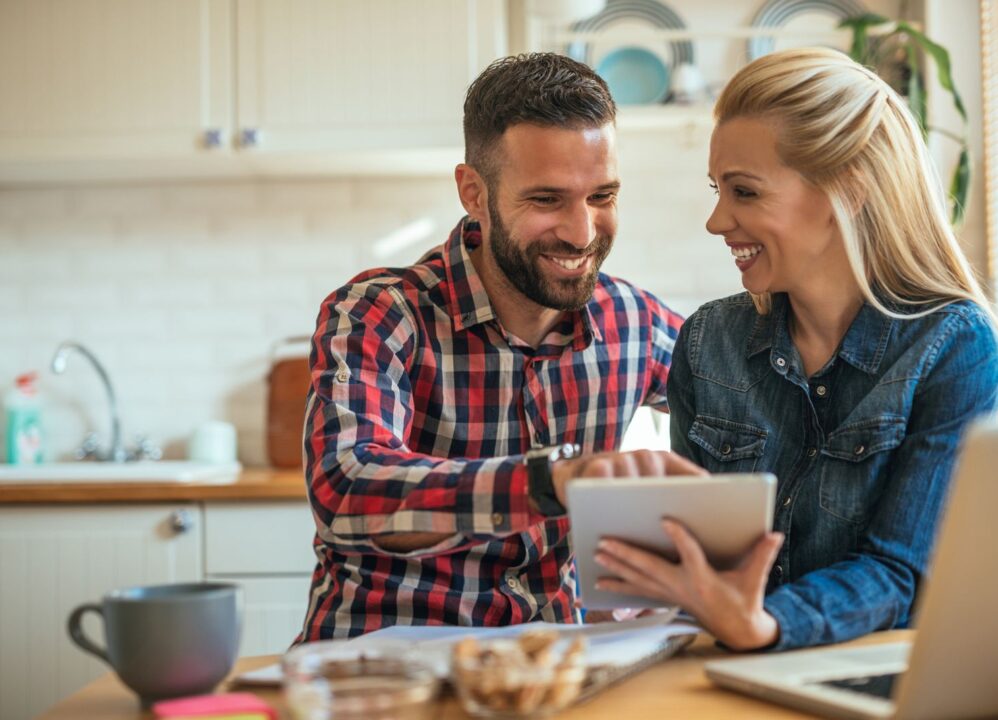 Smiling couple reviewing annuity cash-out options on a tablet at home.
