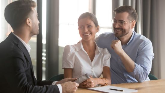 "Smiling couple consulting a financial advisor about annuity cash-out options.