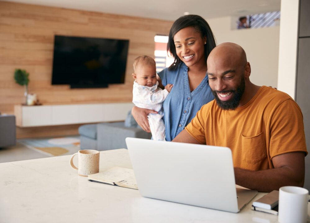 Smiling family using a laptop at home, exploring lump sum settlement options for financial stability.