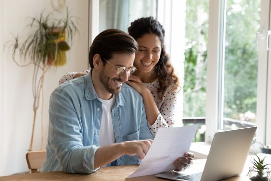 Happy couple reviewing annuity cash-out documents at home on a laptop.