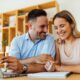 Smiling couple planning finances at home while researching how to sell structured settlement for immediate cash