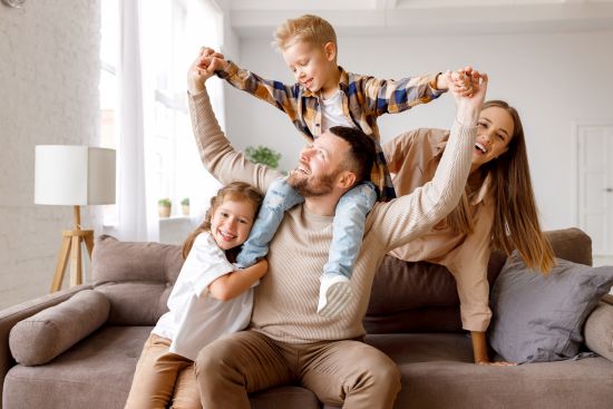 Young family smiling together on couch after taking money out of an annuity to improve their quality of life