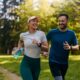 Man and woman running together on a scenic outdoor trail, enjoying a wellness-focused exercise.