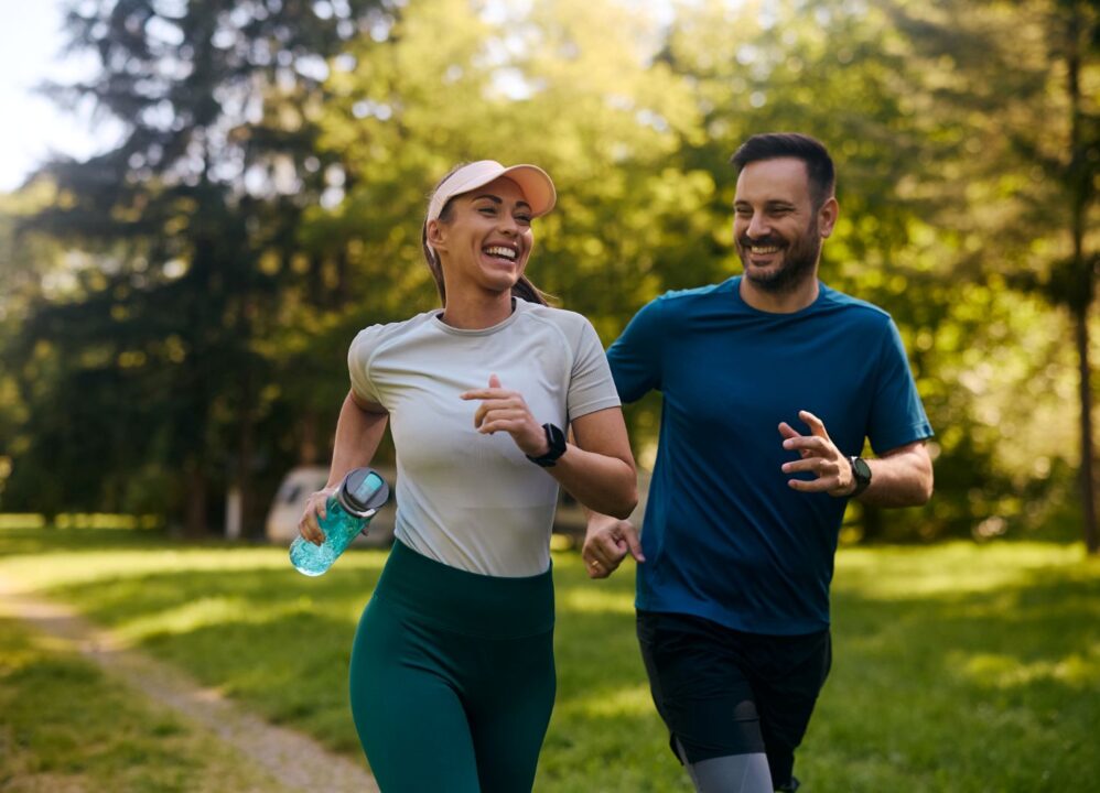 Man and woman running together on a scenic outdoor trail, enjoying a wellness-focused exercise.