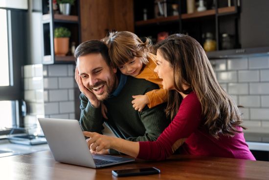 Family happily reviewing financial options together on a laptop.